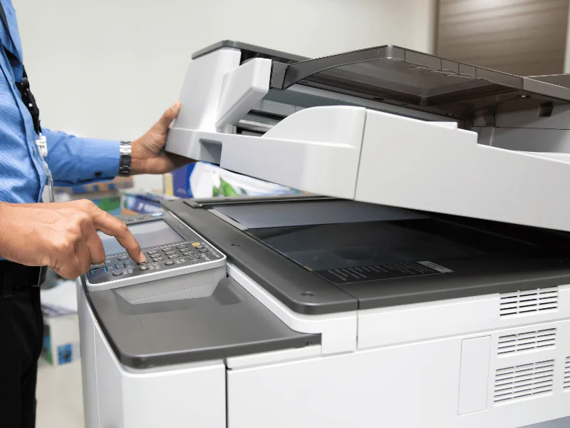 Leasing vs. Buying a Photocopier: Pros and Cons 1 Person pressing start button on a photocopier machine.